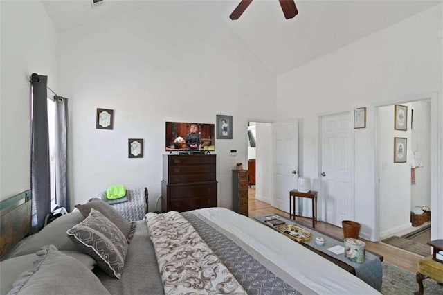 bedroom with high vaulted ceiling, ceiling fan, and light wood-type flooring