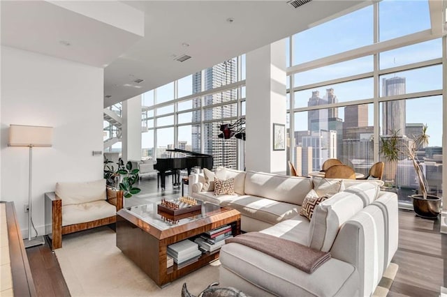 living room with floor to ceiling windows, light hardwood / wood-style flooring, and a high ceiling