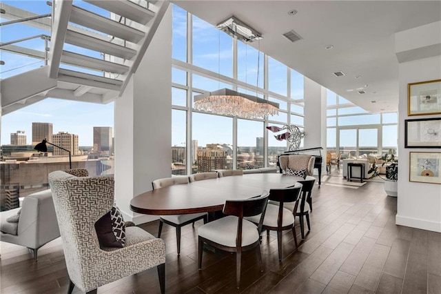 dining room featuring a wealth of natural light, dark wood-type flooring, expansive windows, and a towering ceiling