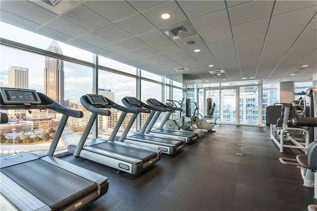 exercise room with a paneled ceiling and expansive windows