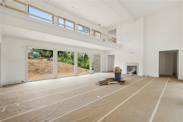 unfurnished living room featuring a high ceiling and beamed ceiling