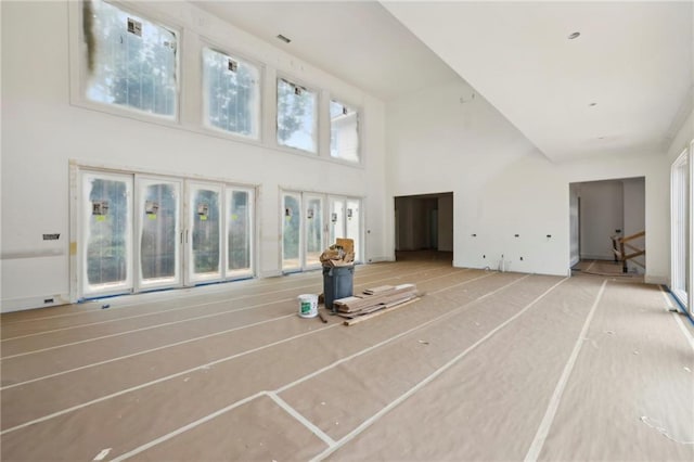 unfurnished living room featuring a towering ceiling