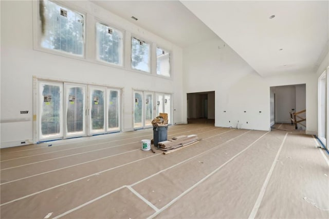 unfurnished living room featuring a towering ceiling and stairway