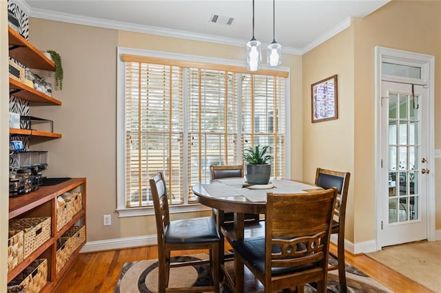 dining space featuring crown molding, wood finished floors, visible vents, and baseboards