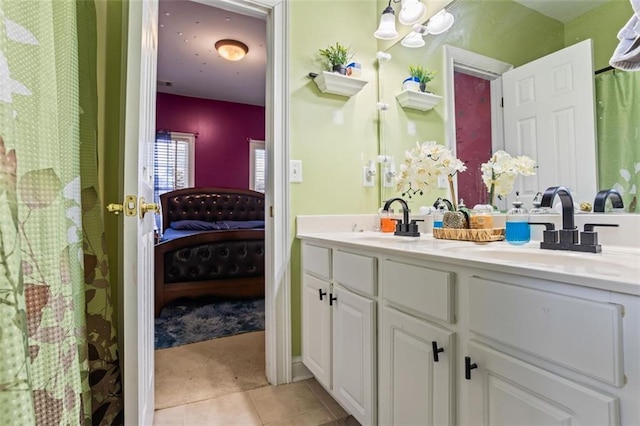 ensuite bathroom featuring a sink, connected bathroom, double vanity, and tile patterned flooring