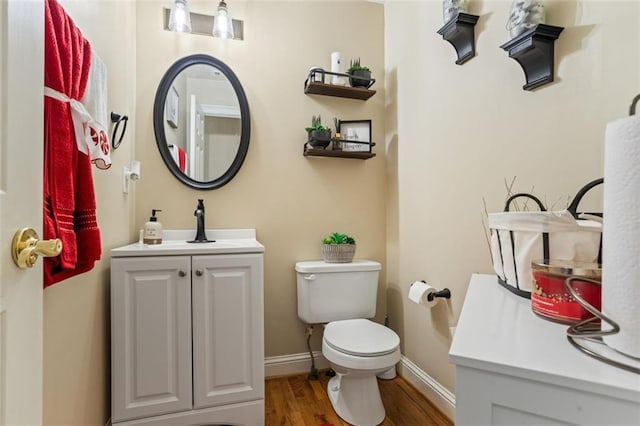 bathroom with vanity, toilet, wood finished floors, and baseboards