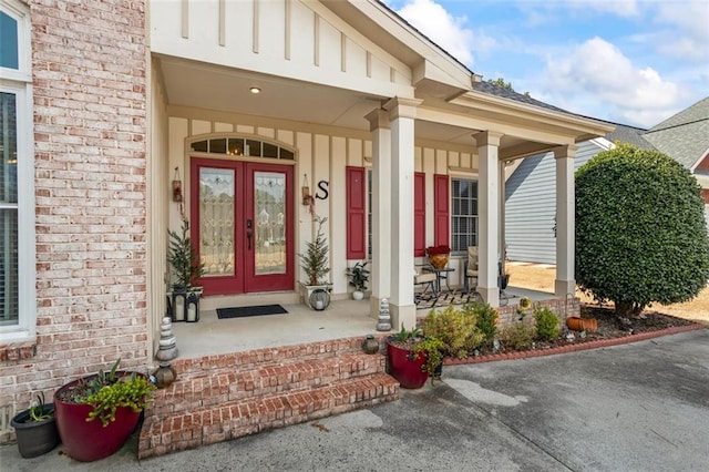 entrance to property with brick siding, french doors, and board and batten siding