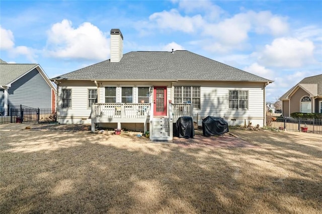 back of property featuring a yard, a deck, a chimney, and a fenced backyard