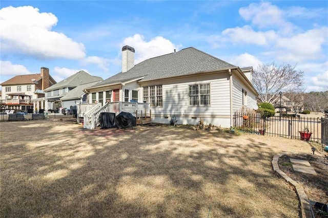 back of house featuring a wooden deck, a chimney, roof with shingles, and fence