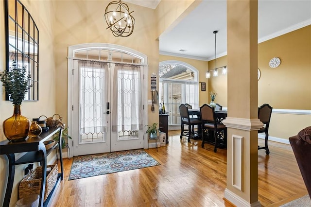 entrance foyer with a notable chandelier, french doors, crown molding, and wood finished floors