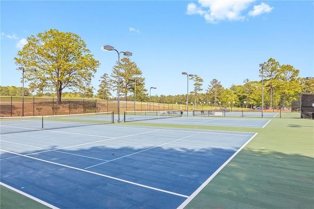 view of tennis court featuring community basketball court and fence