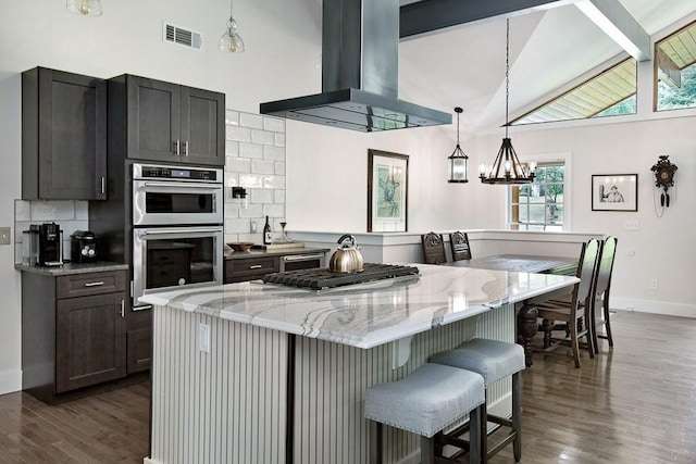 225 Jayne Ellen Way, Alpharetta, GA 30009 - kitchen featuring wall chimney range hood, appliances with stainless steel finishes, dark wood-style flooring, light stone countertops, and a kitchen island