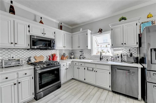 kitchen with white cabinetry, sink, ornamental molding, and appliances with stainless steel finishes