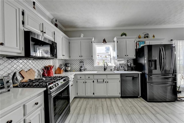 kitchen with white cabinetry, ornamental molding, sink, and black appliances