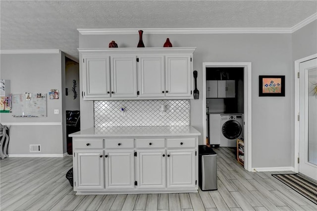 kitchen with white cabinetry, washer / dryer, decorative backsplash, crown molding, and a textured ceiling