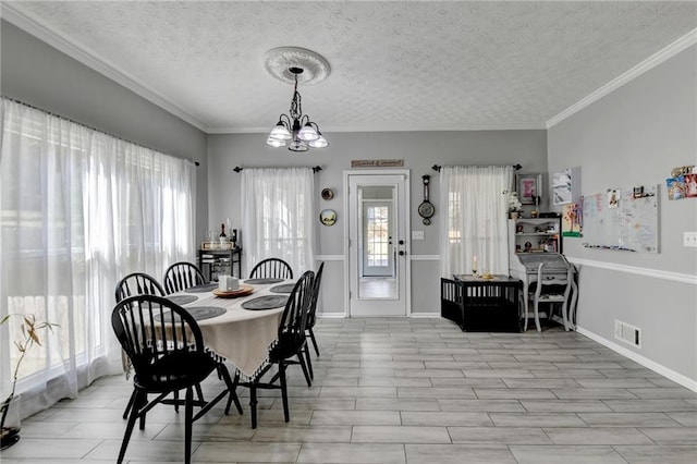 dining room with an inviting chandelier, ornamental molding, and a textured ceiling