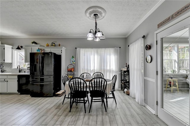 dining area with a notable chandelier, ornamental molding, sink, and a textured ceiling