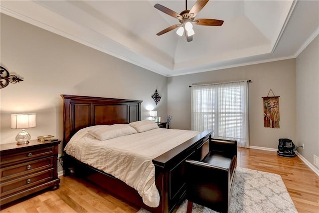 bedroom featuring a raised ceiling, ceiling fan, crown molding, and light hardwood / wood-style floors