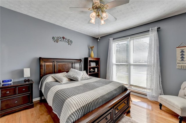 bedroom featuring ceiling fan, a textured ceiling, and light hardwood / wood-style floors