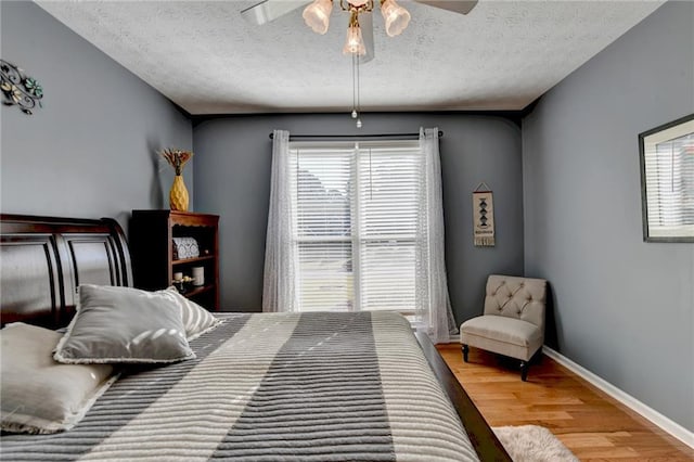 bedroom with multiple windows, hardwood / wood-style floors, and a textured ceiling