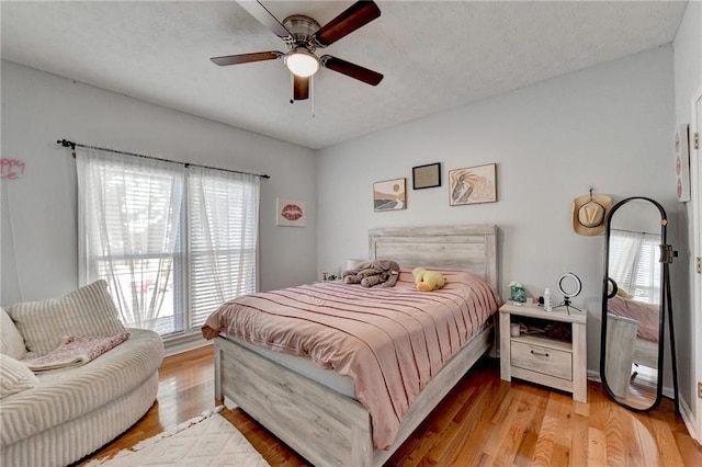 bedroom with ceiling fan, light hardwood / wood-style floors, and a textured ceiling