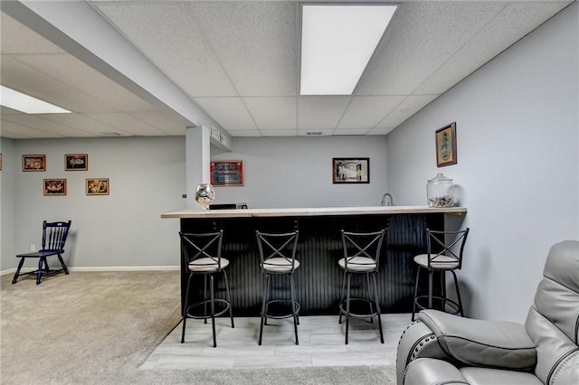 bar featuring carpet floors and a paneled ceiling