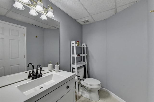 bathroom with a paneled ceiling, vanity, toilet, and tile patterned floors