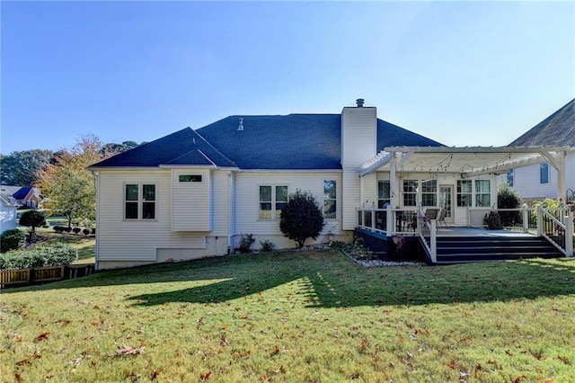 rear view of property with a wooden deck, a pergola, and a lawn