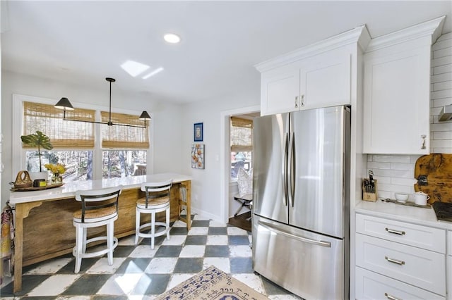 kitchen with white cabinetry, a healthy amount of sunlight, pendant lighting, and stainless steel fridge