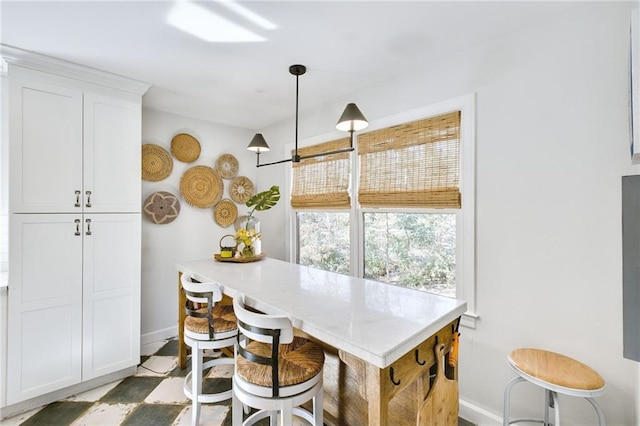 kitchen with a breakfast bar, hanging light fixtures, and white cabinets