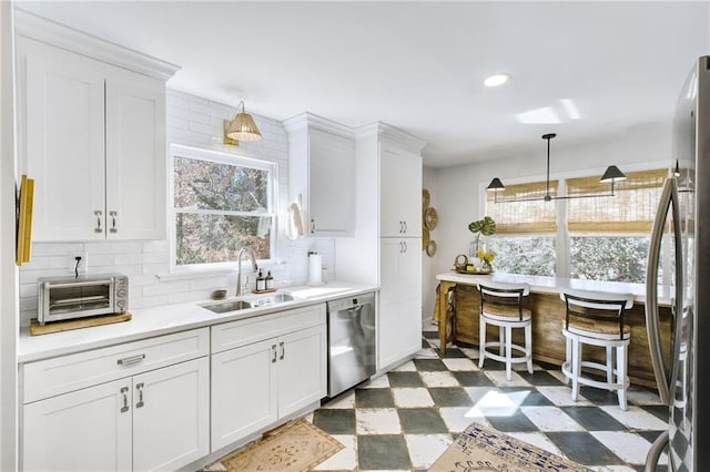 kitchen featuring stainless steel appliances, white cabinetry, sink, and pendant lighting