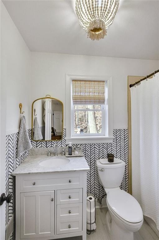 bathroom featuring walk in shower, vanity, toilet, and tile walls