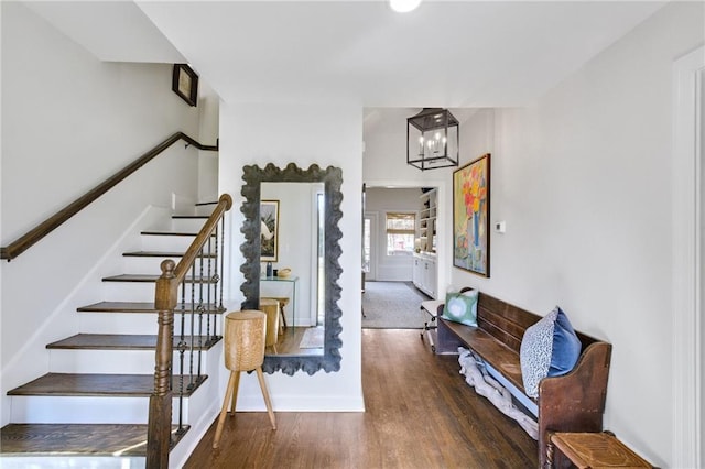 staircase with wood-type flooring and a chandelier