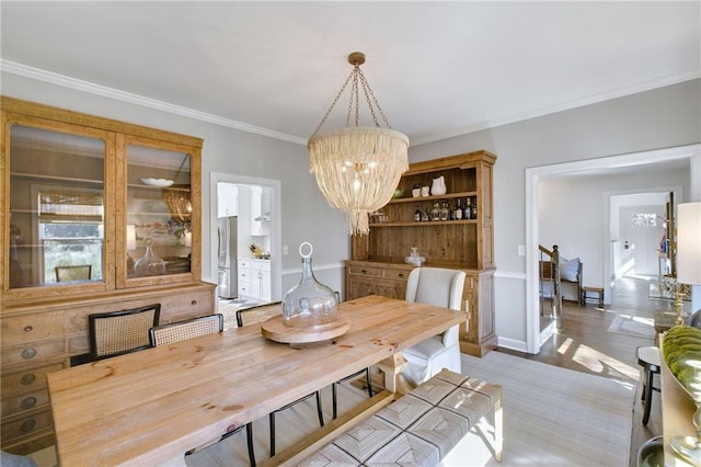 dining room with ornamental molding, light hardwood / wood-style flooring, and a notable chandelier