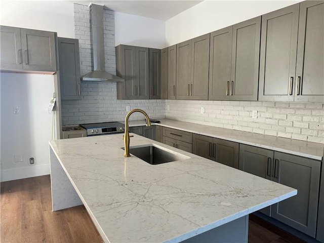 kitchen with dark wood-type flooring, wall chimney exhaust hood, sink, light stone countertops, and backsplash