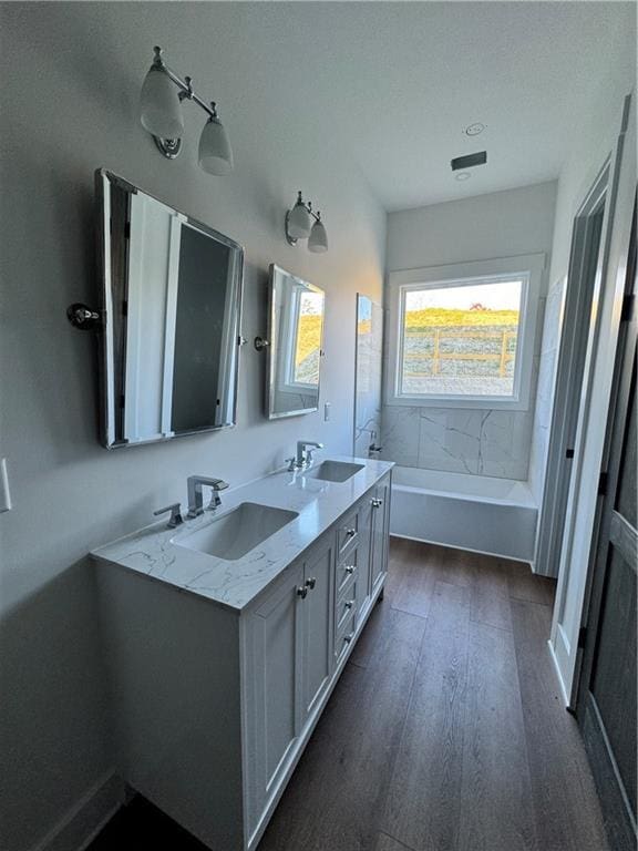 bathroom with a bathing tub, vanity, and wood-type flooring