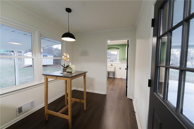 dining room with dark wood-style floors, baseboards, visible vents, and ornamental molding