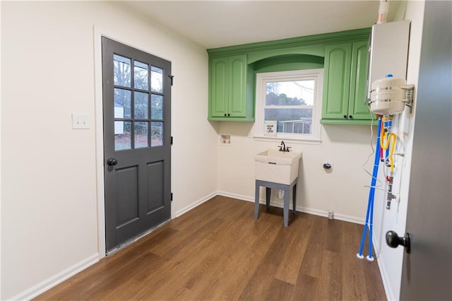 clothes washing area featuring hookup for a washing machine, cabinet space, wood finished floors, plenty of natural light, and baseboards