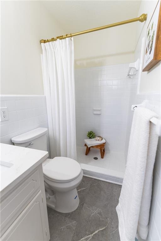 full bath featuring toilet, vanity, tile walls, wainscoting, and a shower stall