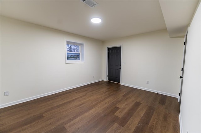 unfurnished room with visible vents, dark wood finished floors, and baseboards