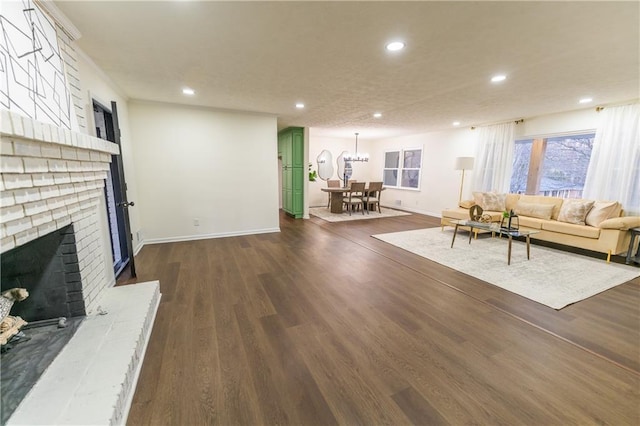 living area with dark wood-type flooring, recessed lighting, and a brick fireplace