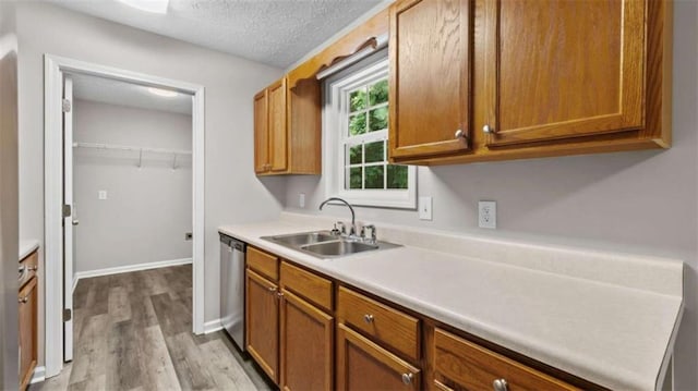 35 Ravenwood Dr, Rockmart, GA 30153 - kitchen with stainless steel dishwasher, light wood finished floors, light countertops, brown cabinetry, and a textured ceiling