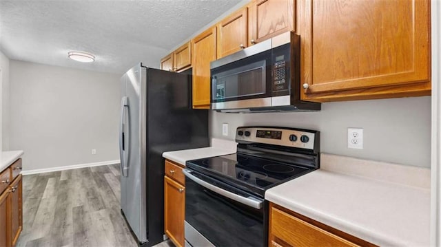 35 Ravenwood Dr, Rockmart, GA 30153 - kitchen with stainless steel appliances, a textured ceiling, light countertops, wood finished floors, and brown cabinetry