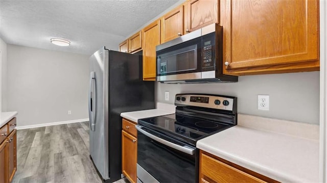 35 Ravenwood Dr, Rockmart, GA 30153 - kitchen featuring appliances with stainless steel finishes, a textured ceiling, light countertops, wood finished floors, and brown cabinetry