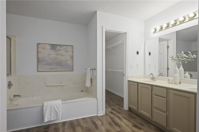 402 Roswell Green Ln, Roswell, GA 30075 - bathroom featuring wood finished floors, a bath, double vanity, a textured ceiling, and a walk in closet