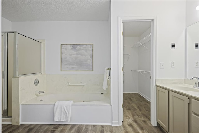 402 Roswell Green Ln, Roswell, GA 30075 - bathroom with vanity, wood finished floors, a garden tub, a stall shower, and a textured ceiling
