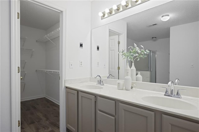 402 Roswell Green Ln, Roswell, GA 30075 - full bathroom with wood finished floors, double vanity, a stall shower, a spacious closet, and a textured ceiling