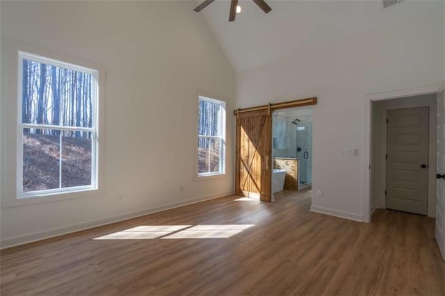 1250 Hays Mill Rd, Carrollton, GA 30117 - unfurnished bedroom with a barn door, high vaulted ceiling, baseboards, wood finished floors, and a ceiling fan
