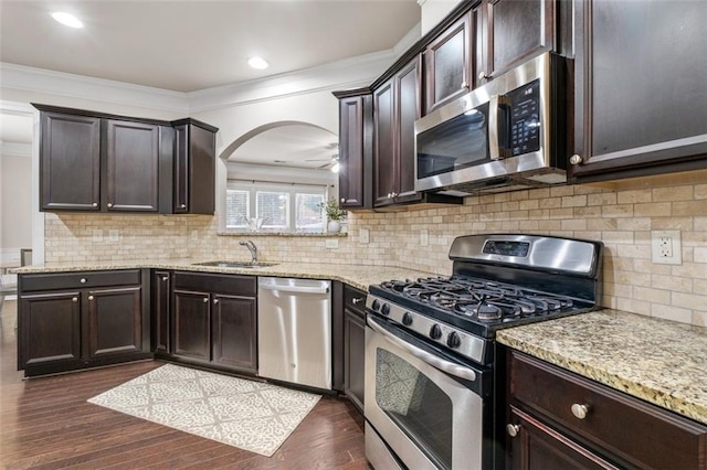 kitchen with sink, ornamental molding, appliances with stainless steel finishes, dark hardwood / wood-style flooring, and decorative backsplash