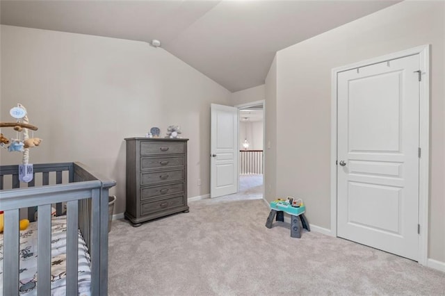 bedroom featuring vaulted ceiling, a nursery area, and light carpet